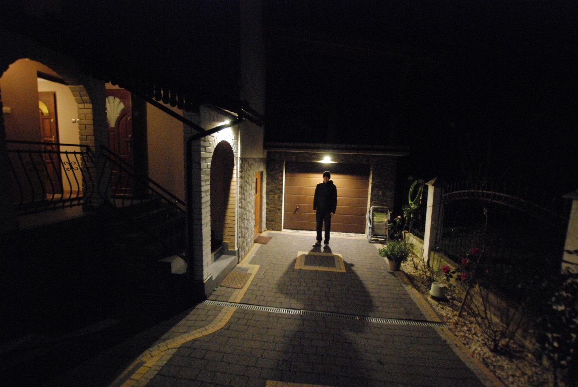 Zdjęćie przedstawia prawidłowe oświetlenie przydomowe skierowane w dół - uzyskano efekt jasnego podjazdu przed domem i braku ucieczki strumienia świetlnego bezpośrednio w górę